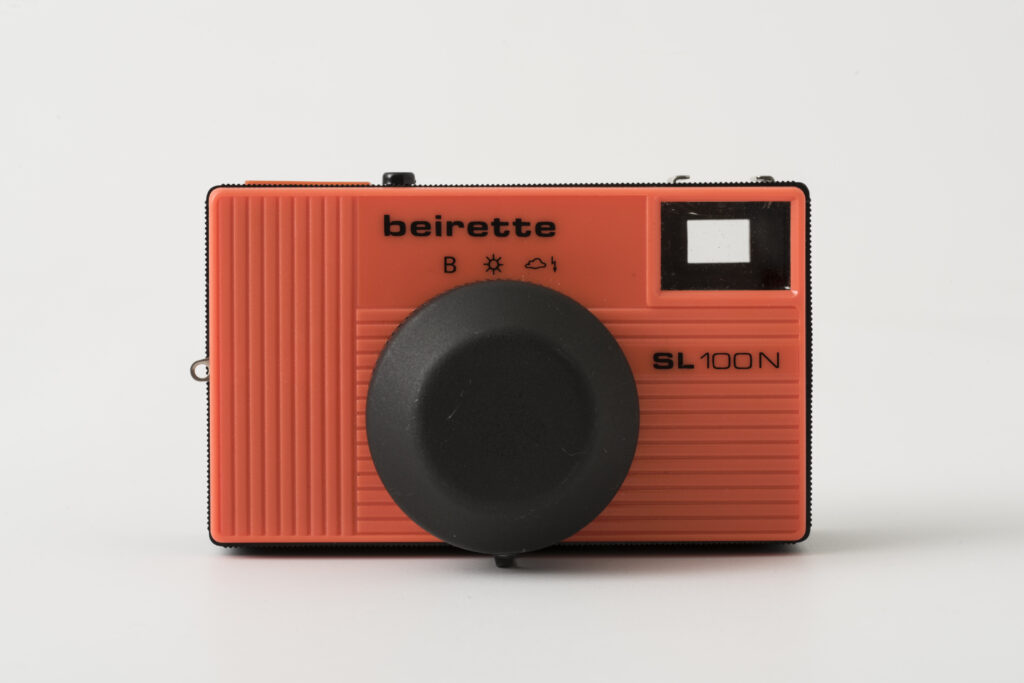 photographic camera, construction based on a black plastic casing with a coloured front shutter in bright orange