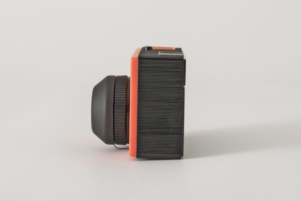 photographic camera, construction based on a black plastic casing with a coloured front shutter in bright orange