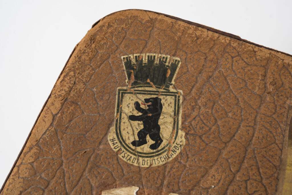 suitcase with a brown leather cover, detail view on a sticker with the Berlin bear