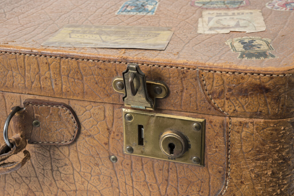 Reisekoffer mit brauem Lederbezug und Aufklebern, Detailansicht der Messingschnalle