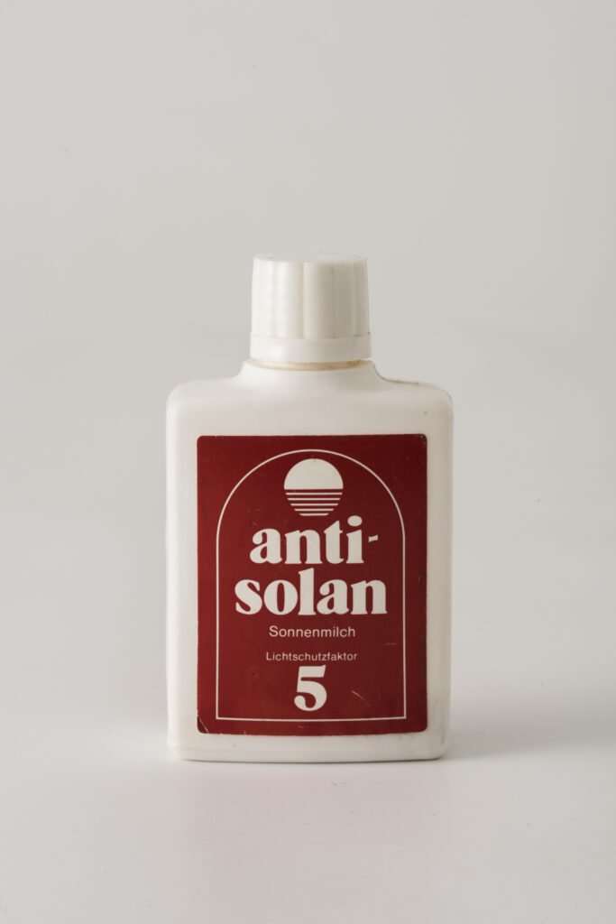 suncream anti-solan in a white pastic bottle with a red label